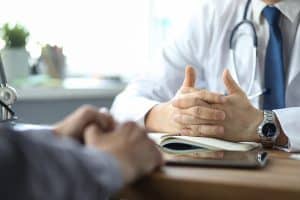 Close-up Of Doctor And Patient Hands While Doctor Listens To Pat